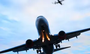 Ein landendes Flugzeug mit ausgefahrenem Fahrwerk im Gegenlicht, ein weiteres Flugzeug fliegt darüber.