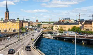 Blick auf die Skyline von Stockholm mit einem Fluss und einer Autobahn, auf der Autos fahren. Das Parken in Stockholm ist hier gut zu sehen.