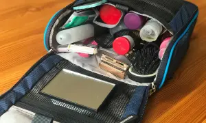 Offener Kulturbeutel mit Kosmetikartikeln: Zahnbürste, Rasierer, Kamm, Spiegel und diverse Fläschchen. Perfekte Packliste für unterwegs.