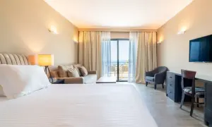 Gemütliches Zimmer im sentido pelagos suites & spa mit Meerblick vom Balkon. Einladendes Bett, Sofa und Schreibtisch.