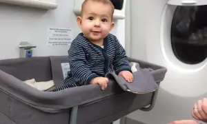 Kleines Baby in Flugzeug-Babywiege, der beste Sitzplatz im Flugzeug mit Kleinkind für eine entspannte Reise.