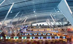 Moderne Flughafenhalle mit vielen Check-in-Schaltern, die für das standby fliegen bereit sind. Die geschwungene Decke und die stützenartige Architektur sind beeindruckend.