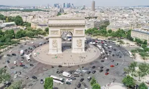 Ein Auto fährt durch Paris, vorbei am Triumphbogen. Die Skyline von Frankfurt ist in der Ferne zu sehen.