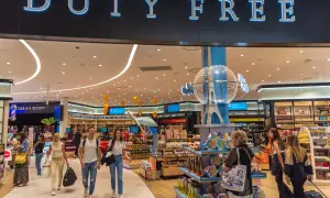 Menschen bummeln durch einen beleuchteten duty free Shop mit vielen Waren.