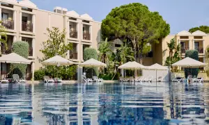 Ein Pool mit Liegen und Sonnenschirmen vor einem Hotelgebäude. Hier beginnt das magic life Belek.