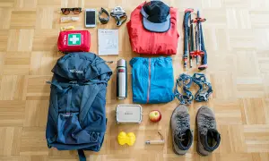 Packliste Bergtour: Rucksack, Wanderschuhe, Steigeisen, Jacken, Mütze, Wanderstöcke, Erste-Hilfe-Set, Thermoskanne, Handy, Sonnenbrille, Karte.