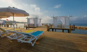 Sonnenliegen und weiße Pavillons auf einem Holzsteg am Meer, ein perfekter Ort für einen Urlaub im Mary Hotel Alanya.