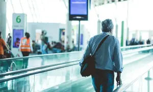 Mann mit Tasche auf Rolltreppe am Flughafen Frankfurt, auf dem Weg zum Geldwechsel.