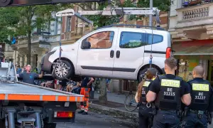Polizei schleppt ein weißes Auto ab. Ein Mann in orangefarbener Arbeitskleidung hilft. Die auto abschleppen kosten sind hier wohl nicht das Thema.