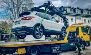 Ein weißer Nissan wird von einem Abschleppwagen in Frankfurt auf die Ladefläche gehoben. Die Abschleppkosten sind hier wohl im Service enthalten.