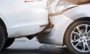 Zwei Autos sind kollidiert, ein weißes und ein silbernes. Der Unfall beim Ausparken hat die Stoßstangen und Scheinwerfer beschädigt.