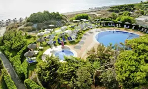 Einladende Pools und Liegen am Strand des Grupotel Natura Playa. Sonnenschirme spenden Schatten.