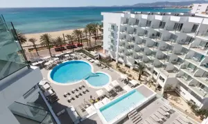 Ein modernes Hotel mit Pools und Liegestühlen, daneben ein Strand mit Palmen und dem Meer. Ein tropischer Traum!