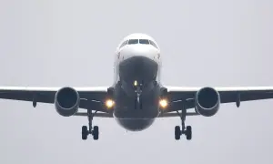 Ein Flugzeug nähert sich mit hoher Geschwindigkeit der Landebahn. Die Lichter am Fahrwerk leuchten hell.
