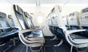 Leere Sitze in einem Flugzeug von Freebird Airlines. Blaue und graue Polster, Bildschirme an den Rückenlehnen.