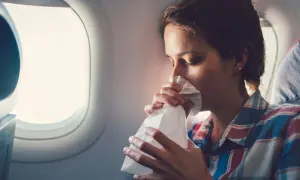 Frau mit Tüte gegen Reisekrankheit im Flugzeug.