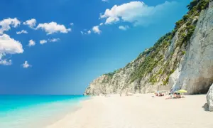 Traumhafter **Griechenland Sandstrand** mit türkisblauem Meer, weißen Klippen und einigen Sonnenanbetern.