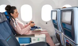 Frau im KLM Flugzeug entspannt sich mit einem kleinen Beutel.