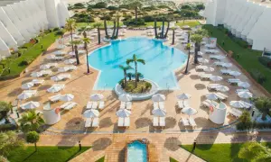Traumhafter Poolbereich mit Liegen und Sonnenschirmen am IBEROSTAR Royal Andalus. Der Strand und das Meer sind im Hintergrund zu sehen.