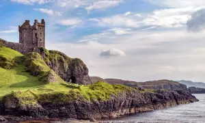 Ruinen einer Burg auf einem grünen Hügel über dem Meer. Schafe grasen friedlich. Was sollte man in Schottland nicht tun? Nicht hierher reisen!