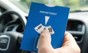 Blaue Parkscheibe mit Ankunftszeit-Einstellung im Auto. Beachten Sie die Regeln zum Parken mit Parkscheibe nach 18 Uhr.