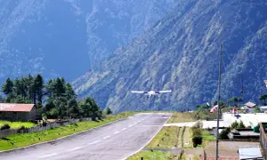 Flugzeug landet auf dem Lukla Airport, umgeben von steilen, bewaldeten Bergen.
