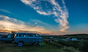 Sonnenuntergang auf einem Campingplatz mit vielen Fahrzeugen, die sich den Platz teilen.