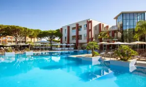 Einladender Poolbereich mit Palmen und Liegestühlen. Das Hotel mit moderner Architektur und dem TUI Kids Club Barrosa Garden verspricht einen tollen Urlaub.