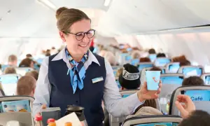 Flugbegleiterin von TUI fly bietet Kaffee an. Ein Lächeln und ein Getränk für die Passagiere.
