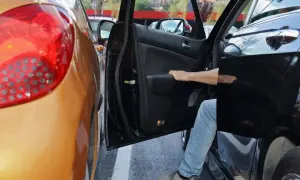 Ein Mann steigt aus seinem Auto, das auf einem Privatparkplatz zu nah an ein anderes Fahrzeug geparkt wurde. Ein kleiner Unfall ist passiert.