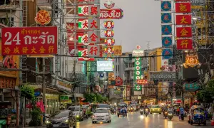Bunte Neonschilder und Verkehr in Bangkok. Ein lebendiges Bild, das die pulsierende Atmosphäre und die einzigartigen Bangkok Erfahrungen widerspiegelt.