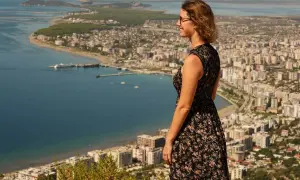 Frau genießt den Ausblick auf eine Stadt am Meer während ihres Urlaubs in Albanien.
