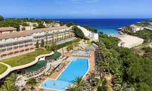 Blick auf das TUI Kids Club Cala Mandia Resort mit Pools, Strand und Meer.