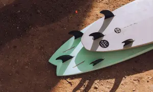 Zwei Surfbretter mit Finnen liegen auf sandigem Boden. Perfekt für die packliste surfcamp.