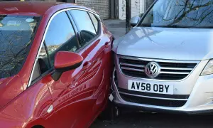 Mein parkendes Auto wurde angefahren. Ein rotes Auto ist seitlich gegen einen silbernen VW gestoßen.