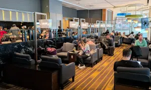 Gemütliche Sitzecken und ein Buffetbereich in einer **priority lounge**. Reisende entspannen sich, arbeiten oder essen.