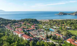 Luftaufnahme des TUI Blue Sarigerme Park mit Blick auf das Meer, Pools und Tennisplätze, eingebettet in üppige grüne Bäume.