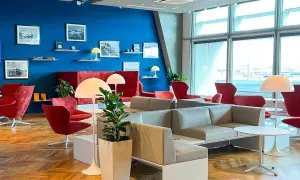 Gemütliche Lounge mit roten Sesseln und grauen Sofas, ideal für Reisende mit Priority Pass Stuttgart.