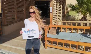 Frau in Hurghada Kleidung, mit Sonnenbrille, hält ein Schild von Peter Tours. Sie trägt Jeans und ein weißes Oberteil.