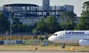 Lufthansa Airbus A320-200 auf dem Rollfeld in Frankfurt. Im Hintergrund ein Parkhaus und Bäume.