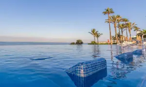 Infinity-Pool mit Blick auf das Meer und Palmen am Riu Palace Meloneras. Entspannung pur im blauen Wasser.