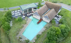 Beech Resort Plauer See: Einladender Poolbereich mit Liegen und moderner Architektur, umgeben von Grün.