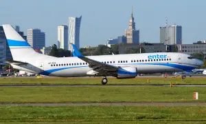 Ein Enter Air Flugzeug rollt auf dem Rollfeld, die Skyline von Warschau im Hintergrund.