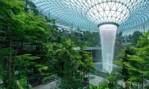 Imposanter Wasserfall im tropischen Garten des Flughafens Singapur. Die beeindruckende Architektur und üppige Vegetation lassen die **Singapur Flughafen Kosten** vergessen.