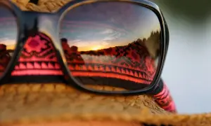 Sonnenuntergangsreflexion in Sonnenbrille auf einem Strohhut. Perfekt für die Packliste Brasilien, mit einem Hauch von Ethno-Muster.