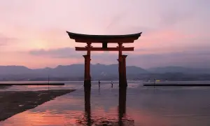 Ein rotes Torii-Tor im Wasser bei Sonnenuntergang. Ein unvergesslicher Moment auf einem Japan Urlaub.