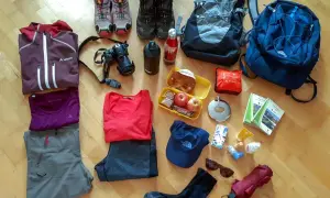 Packliste Wandern Tagestour: Kleidung, Rucksack, Kamera, Verpflegung, Trinkflasche, Wanderstiefel, Sonnenbrille, Regenschirm und Karten für die Tour.