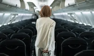 Frau mit Koffer im Gang eines leeren Flugzeugs, bereit für ihren Flug. Sie hat den **priority flughafen** Service gebucht.