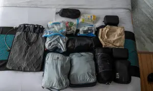 Packliste Thailand: Gepäckstücke, Kulturbeutel und Kleidung sind ordentlich auf dem Bett ausgebreitet.