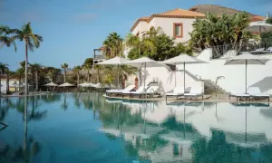 Traumhafter Poolbereich mit Liegen und Sonnenschirmen im Dreams Madeira Spa & Marina. Palmen und ein elegantes Gebäude im Hintergrund.